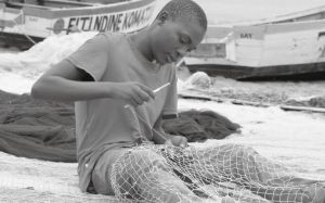渔夫在岸边缝补渔网