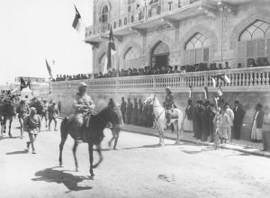 图1-6 1920年6月，费萨尔国王骑着白马在阿勒颇巴龙酒店（Hotel Baron）前检阅军队。