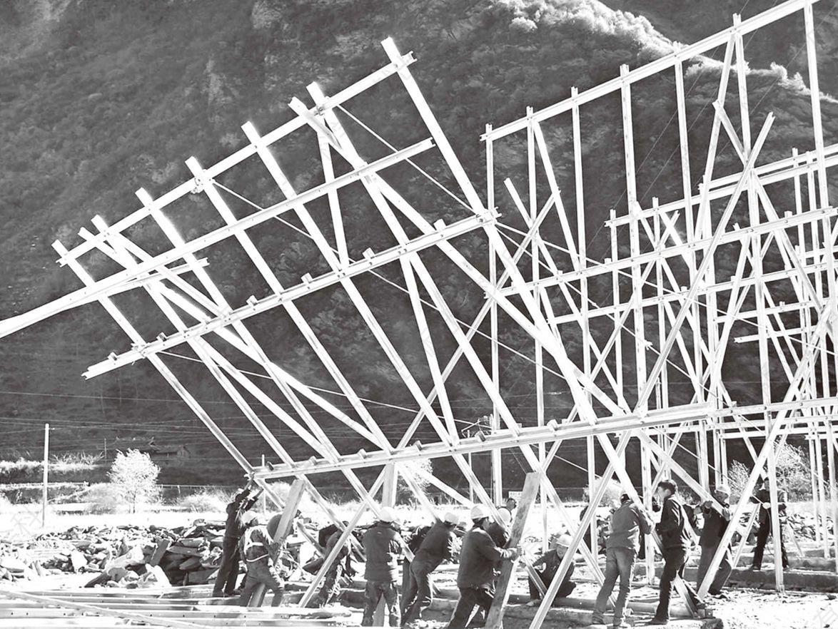 照片1 村民组织成的钢架队立房梁的实况
